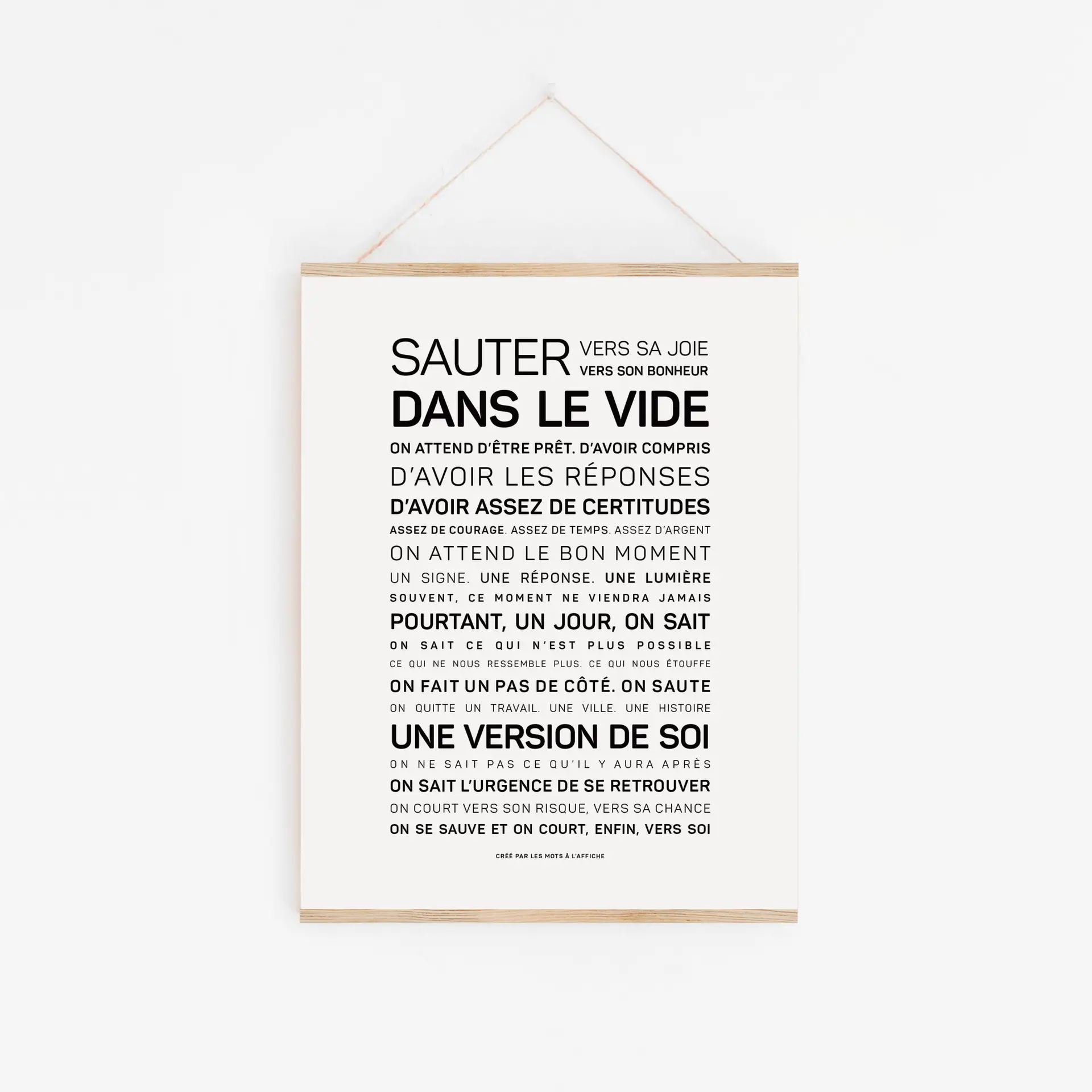 Affiche minimaliste intitulée « Dans cette école, on a le droit (Copie) », comportant un texte en français en caractères gras sur la quête de la joie, de la certitude et de la découverte de soi, accrochée à un mur blanc à l'aide d'un cadre en bois et d'une ficelle.